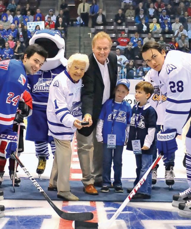 Kitchener Rangers' Ryan Murphy, Mayor Hazel McCallion, Steelheads owner Elliott Kerr, Kerr's son and daughter, and captain Stuart Percy ready to launch the new franchise's first season. Photo by Terry Wilson/OHL Images Google image from http://mississaugalife.ca/wp-content/uploads/2012/11/steelheads-pic.jpg.